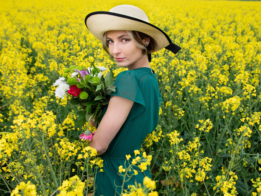 Красивая девушка в шляпе на поле с желтыми цветами летом