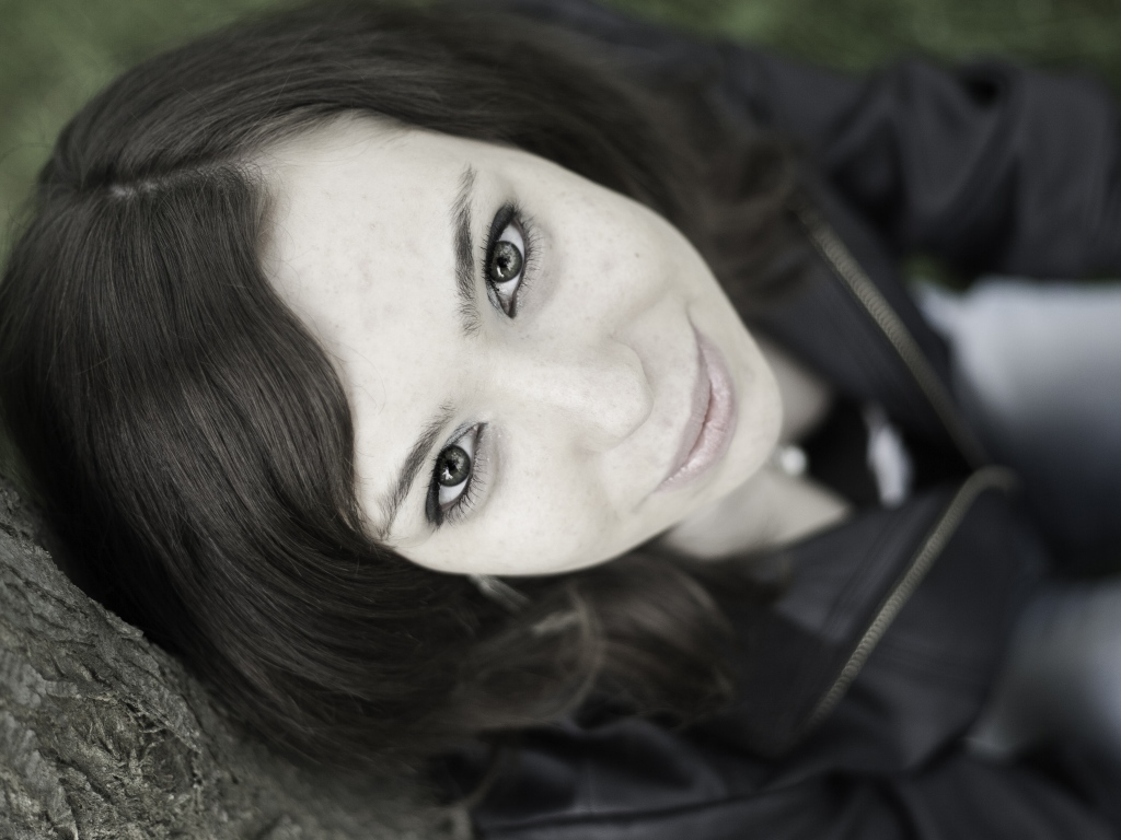 Красивая девушка смотрит вверх сидя под деревом  