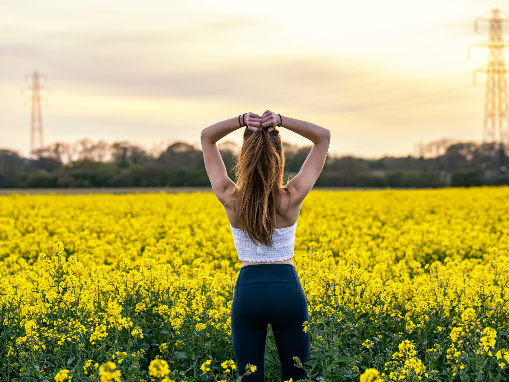 Красивая девушка стоит на поле с рапсом