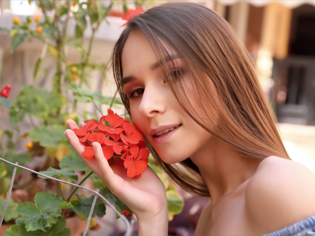 Красивая девушка с красным цветком герани 