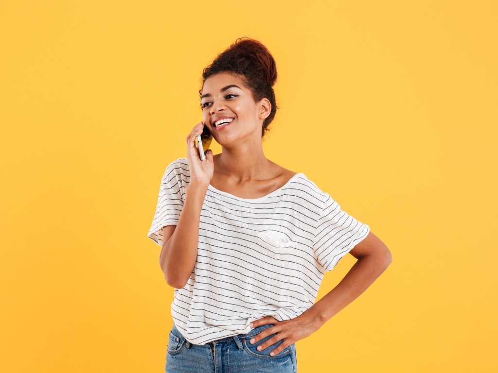 Красивая девушка со смартфоном на желтом фоне