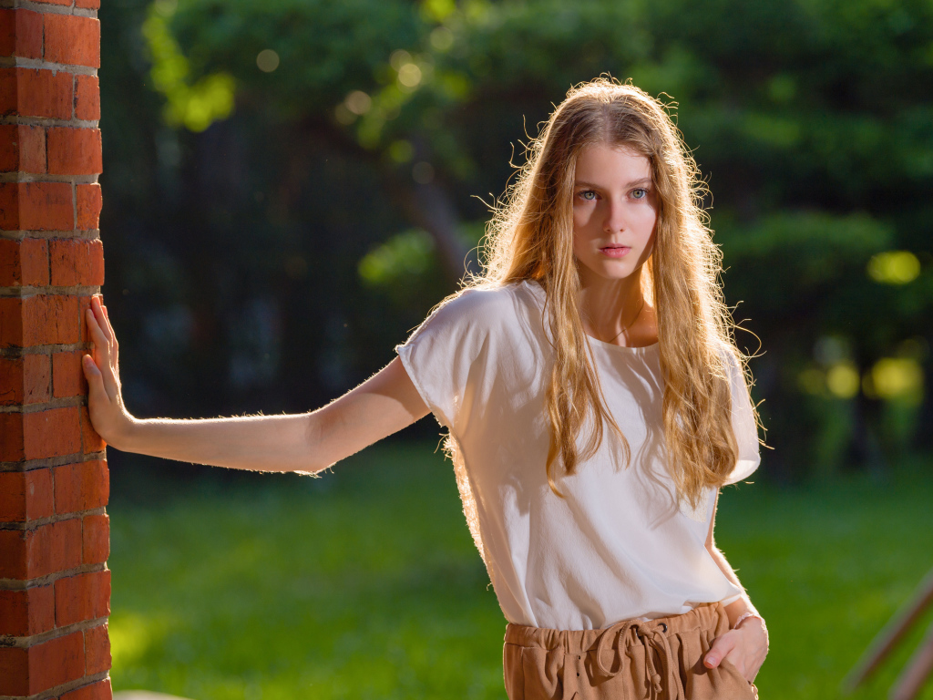 Красивая нежная девушка стоит у стены 