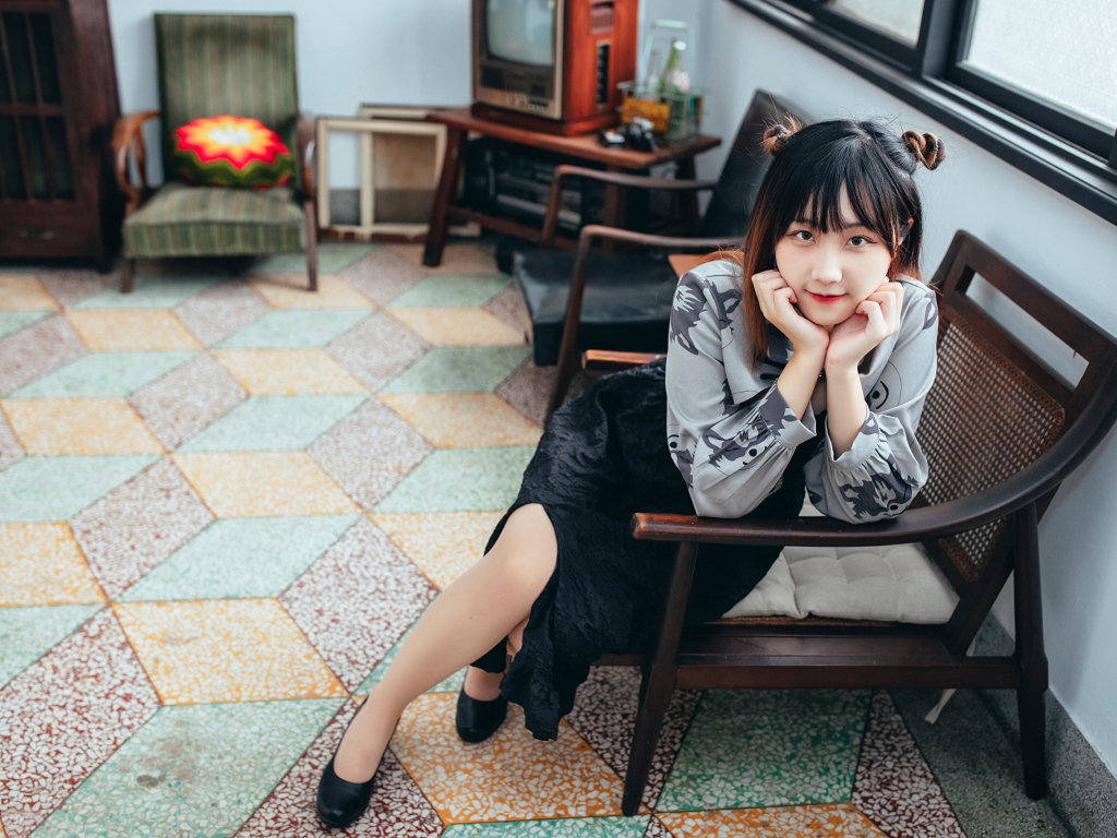 Красивая молодая азиатка сидит в кресле