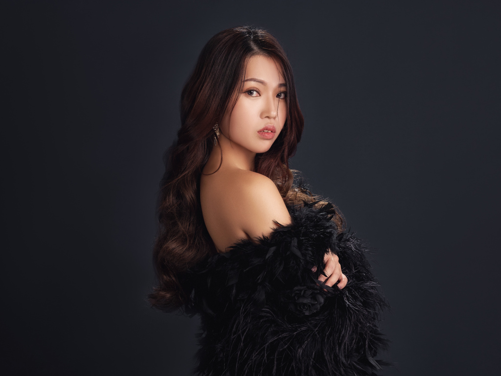 Милая девушка азиатка в черном наряде на сером фоне