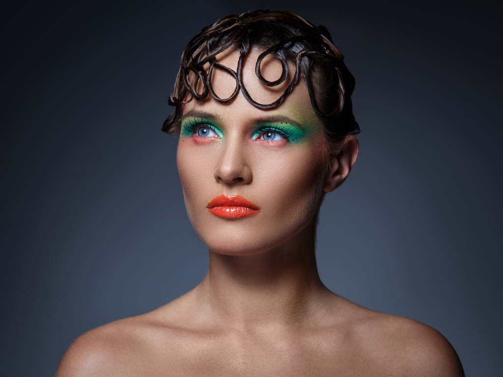 Девушка с ярким макияжем на сером фоне 