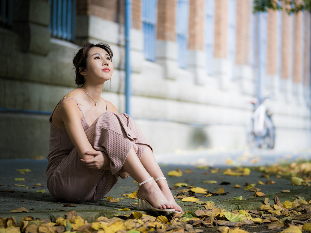 Молодая девушка азиатка сидит на земле с листьями 