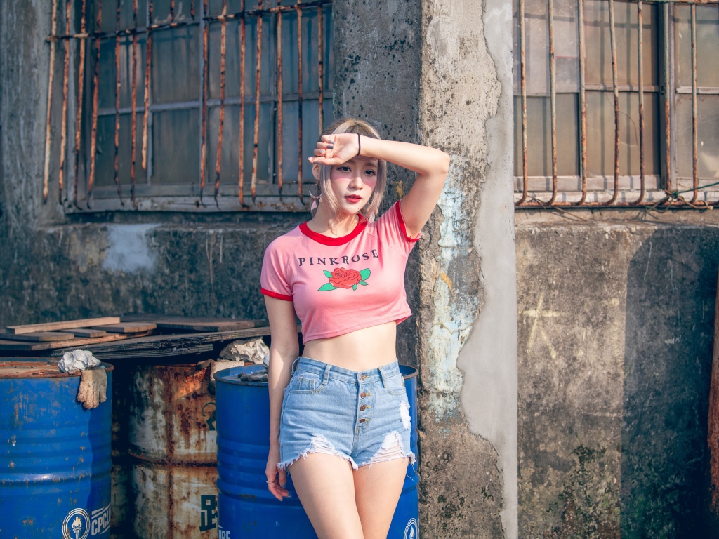 Молодая азиатка стоит у стены 