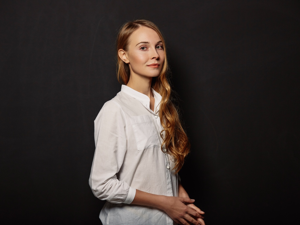 Молодая девушка в белой рубашке на фоне черной стены 