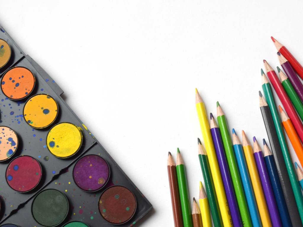 Разноцветные карандаши и краски на белом фоне