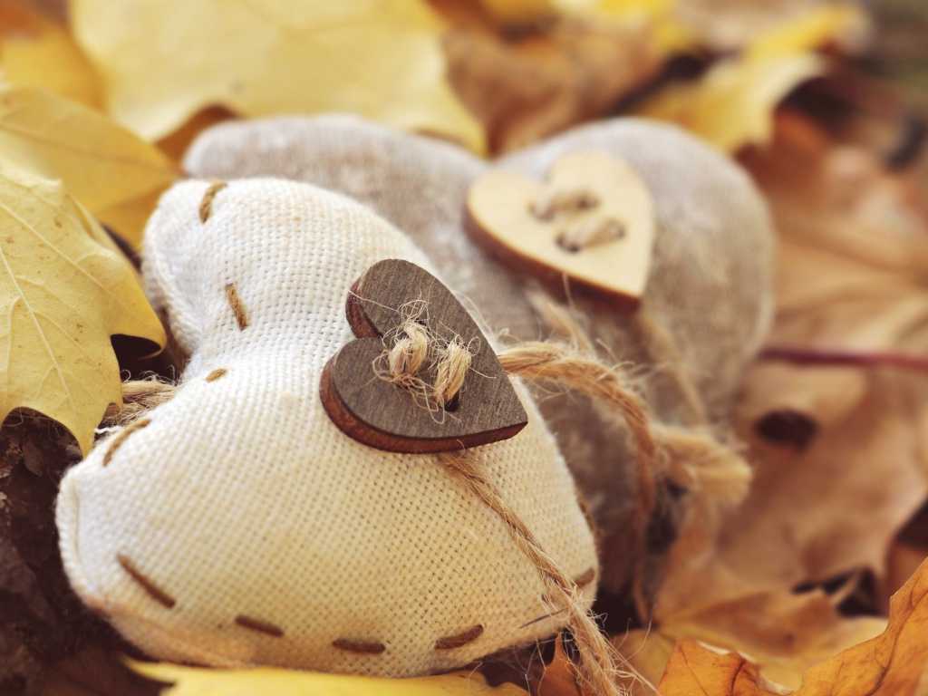 Два сердца из ткани лежит на земле с листьями 