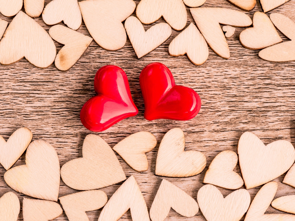 Два красных сердца и деревянные сердечки на столе