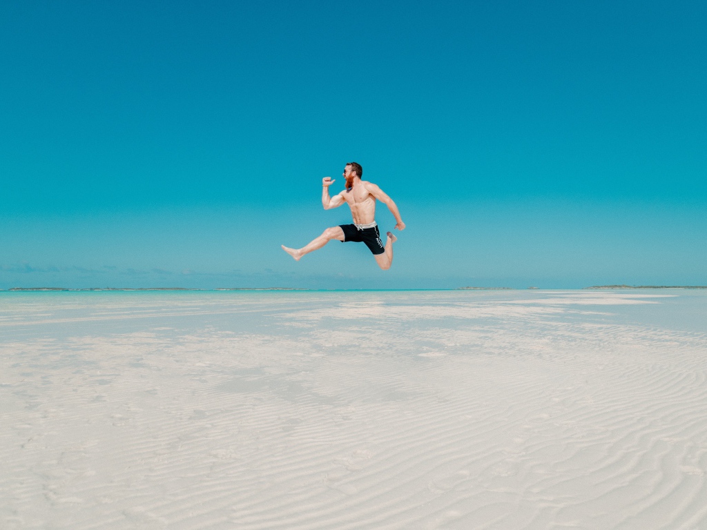 Довольный мужчина прыгает в воде на голубом фоне 