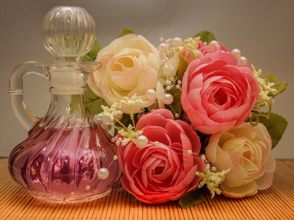 Красивый букет искусственных роз на столе с духами