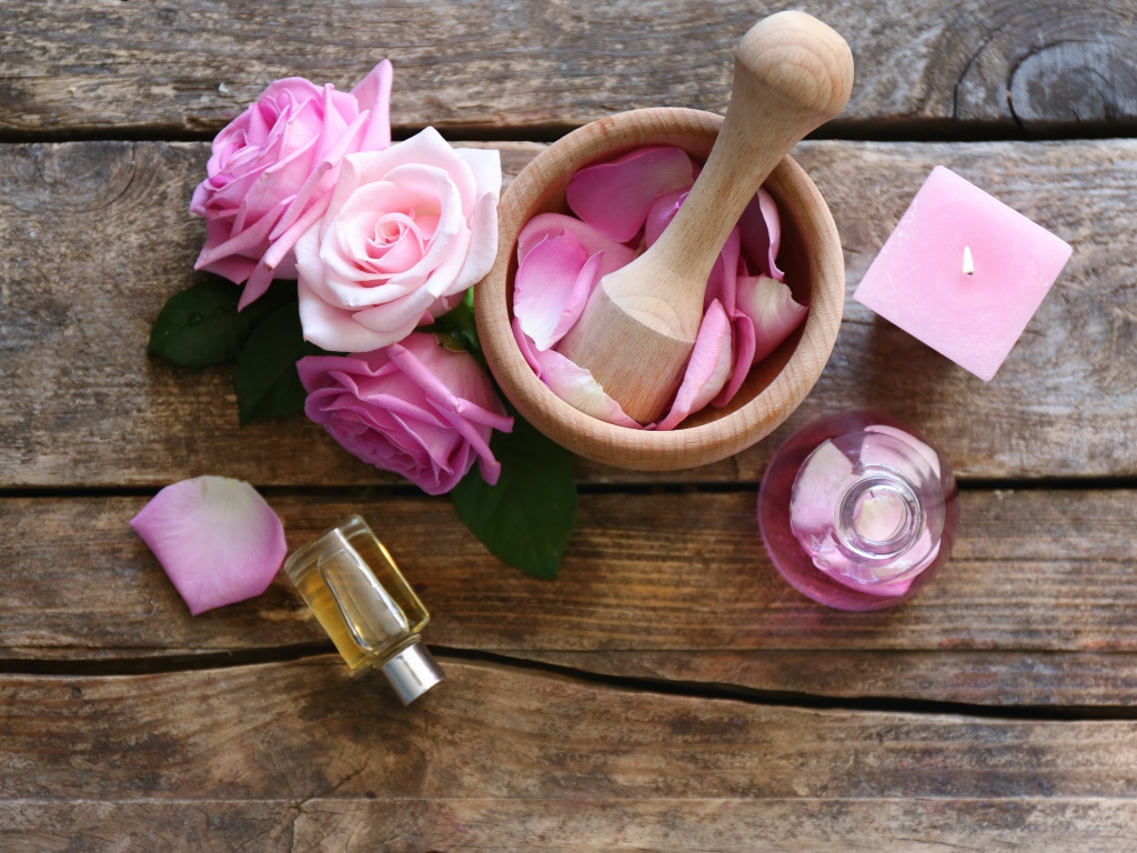 Лепестки розовой розы в ступке на столе с маслом