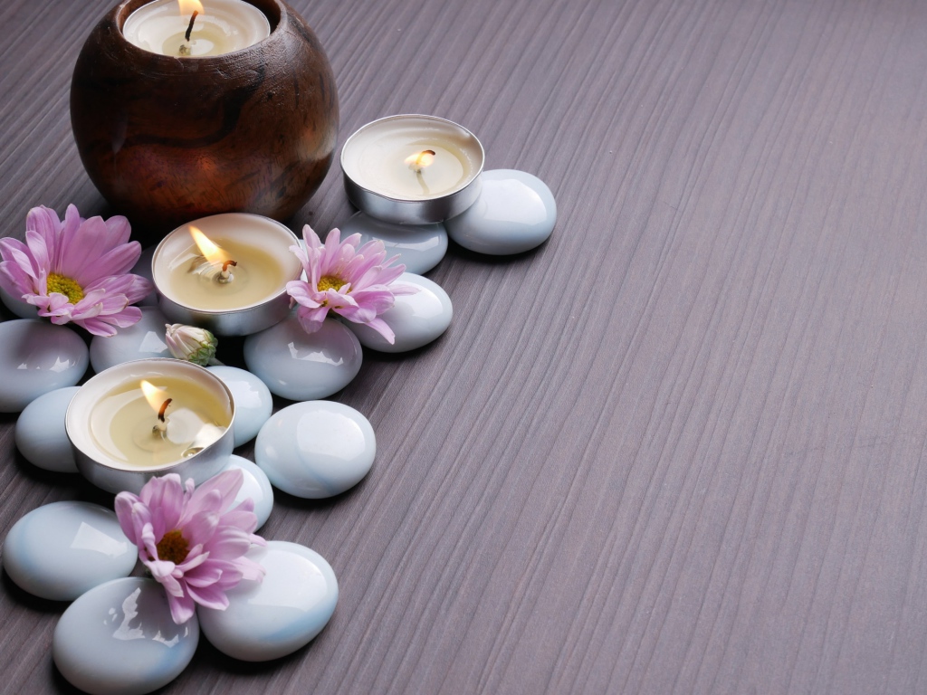 Камни с хризантемами и зажженными свечами на столе 