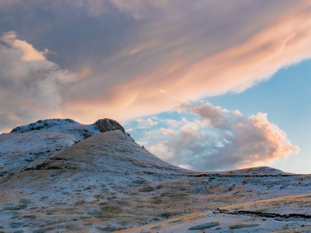 Красивые серые облака над заснеженной горой 