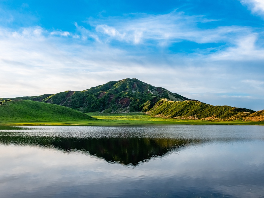 Красивый вид на покрытую зеленью гору под голубым небом у озера