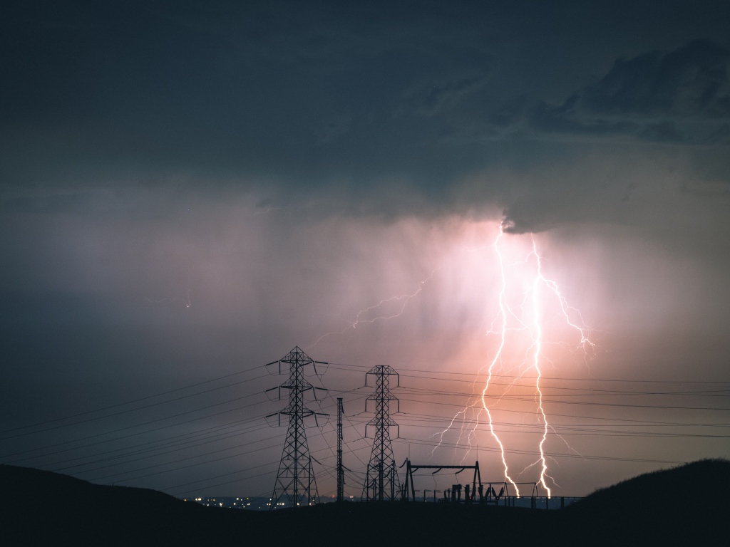 Яркая молния в небе над высоковольтной линией 