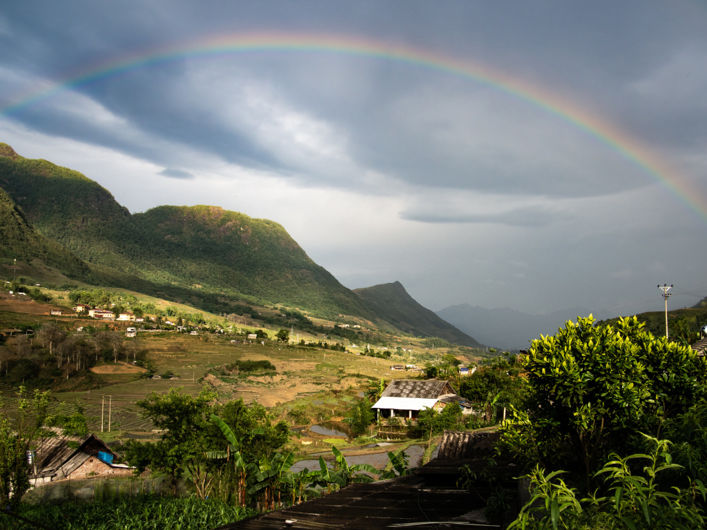 Большая разноцветная радуга в небе над горами