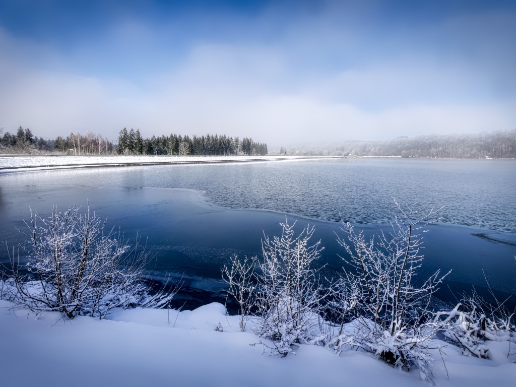 Покрытая льдом река  с заснеженными берегами зимой