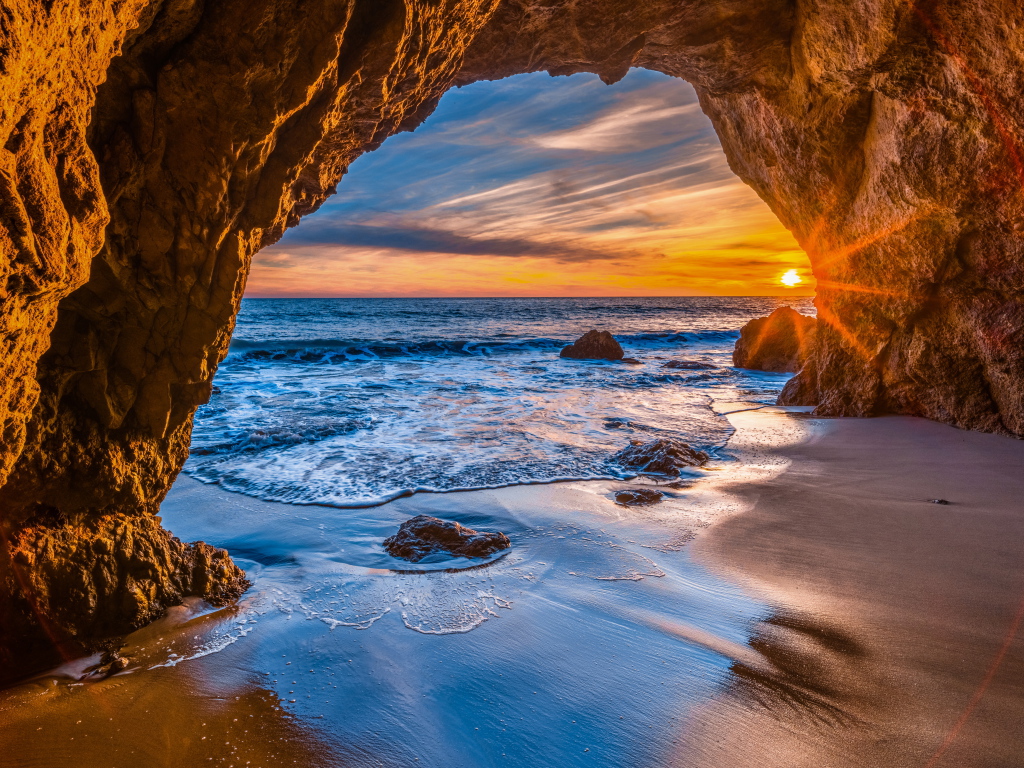Закат солнца в каменной арке в море
