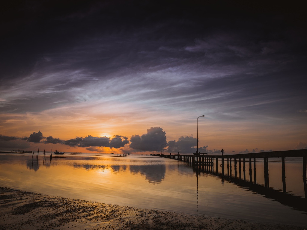 Деревянный мост на реке в лучах  солнца на закате