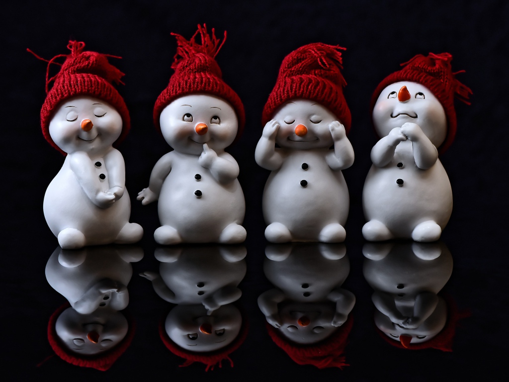 Маленькие статуэтки снеговики на черном фоне