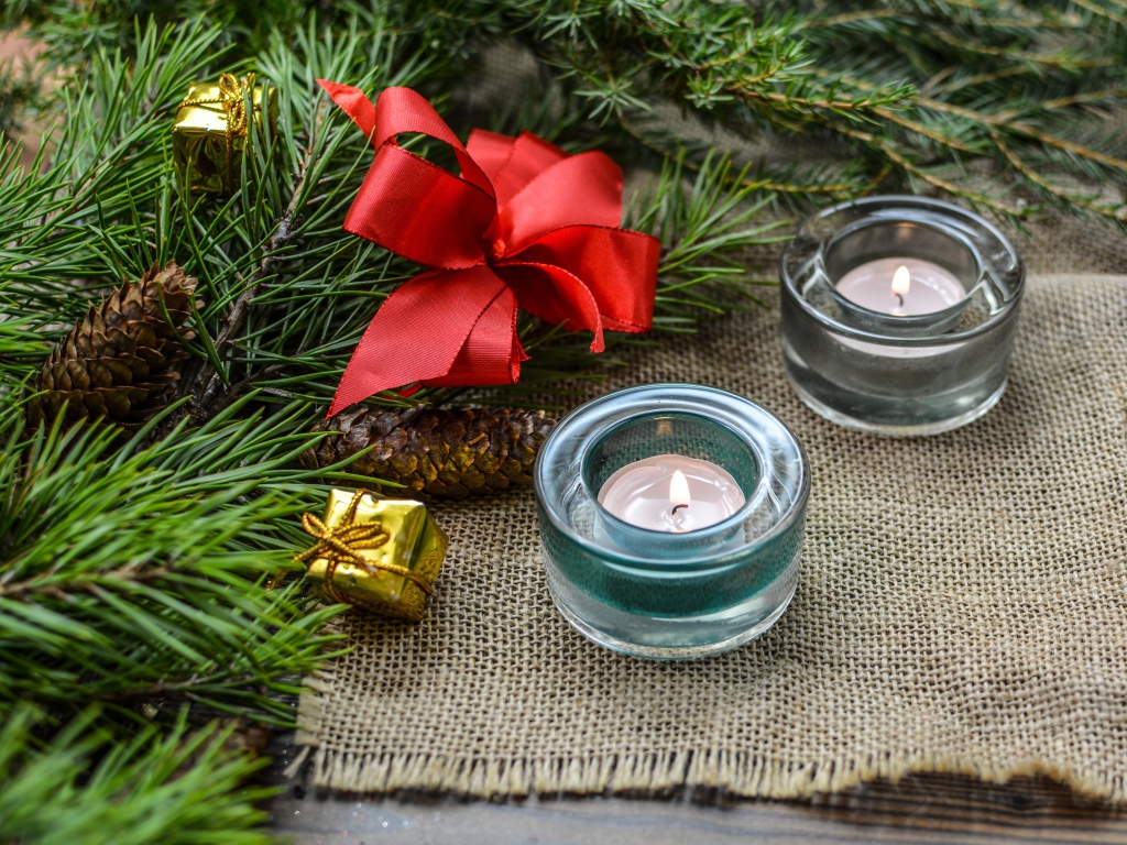 Две зажженные свечи, еловая ветка и красный бант на рождество 