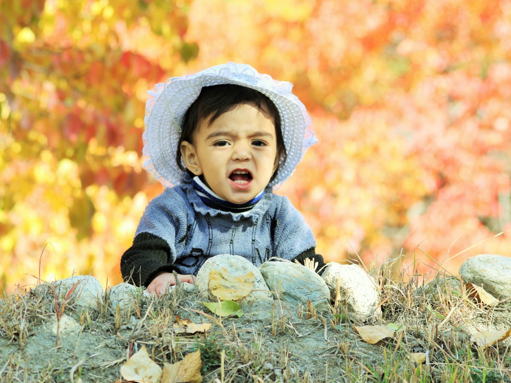 Маленькая девочка в шляпке сидит на земле
