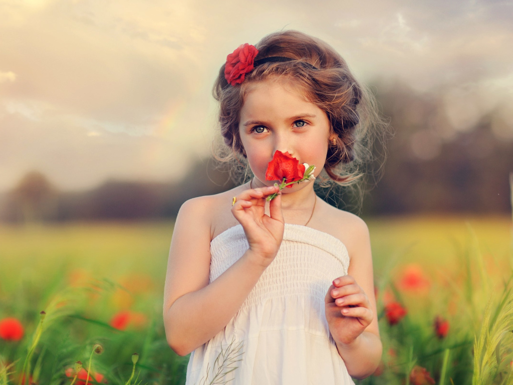 Красивая девочка в белом платье с цветком красного мака в руке 