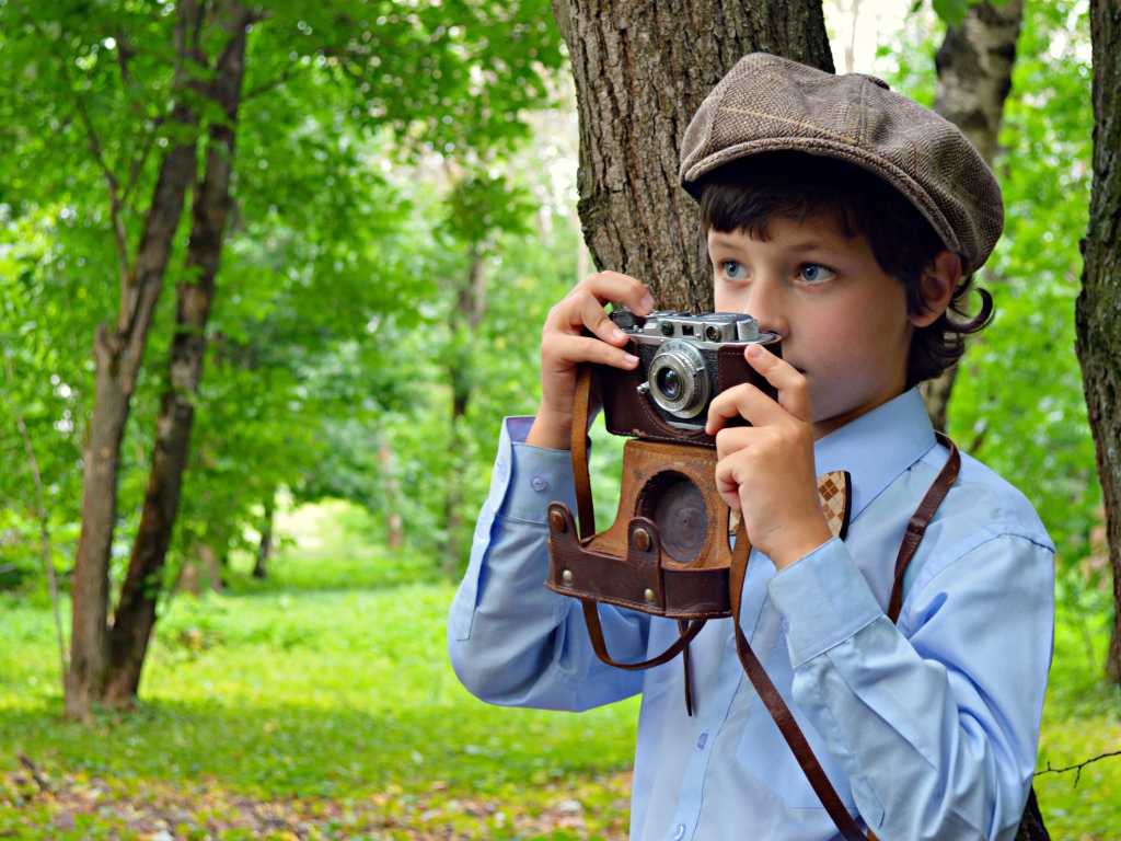 Мальчик с фотоаппаратом в руках в парке
