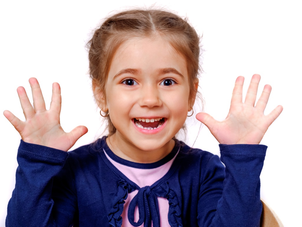 Веселая маленькая девочка с поднятыми руками