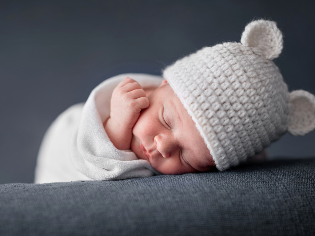 Милый спящий ребенок в белой шапке с ушками