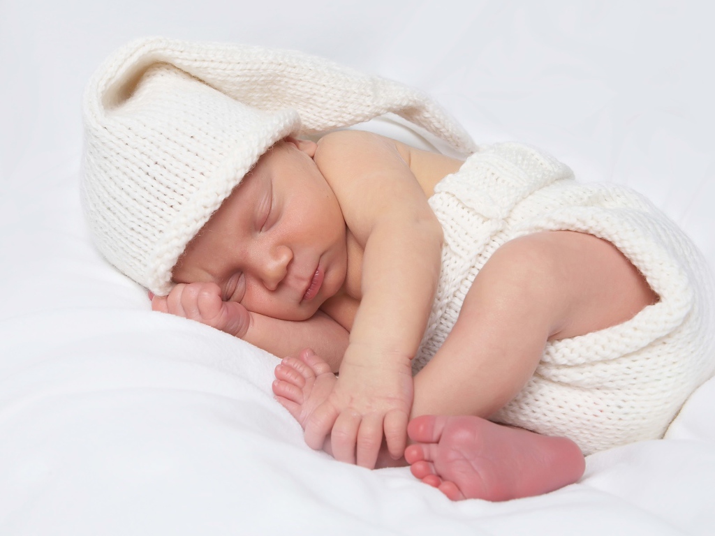 Нежный новорожденный ребенок в белом костюме