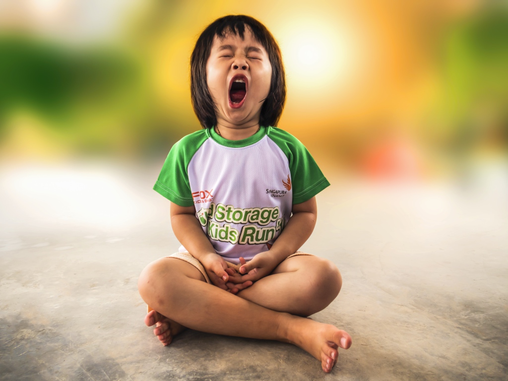 Маленькая девочка азиатка зевает на полу