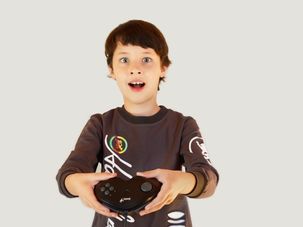 Маленький мальчик с приставкой на сером фоне 