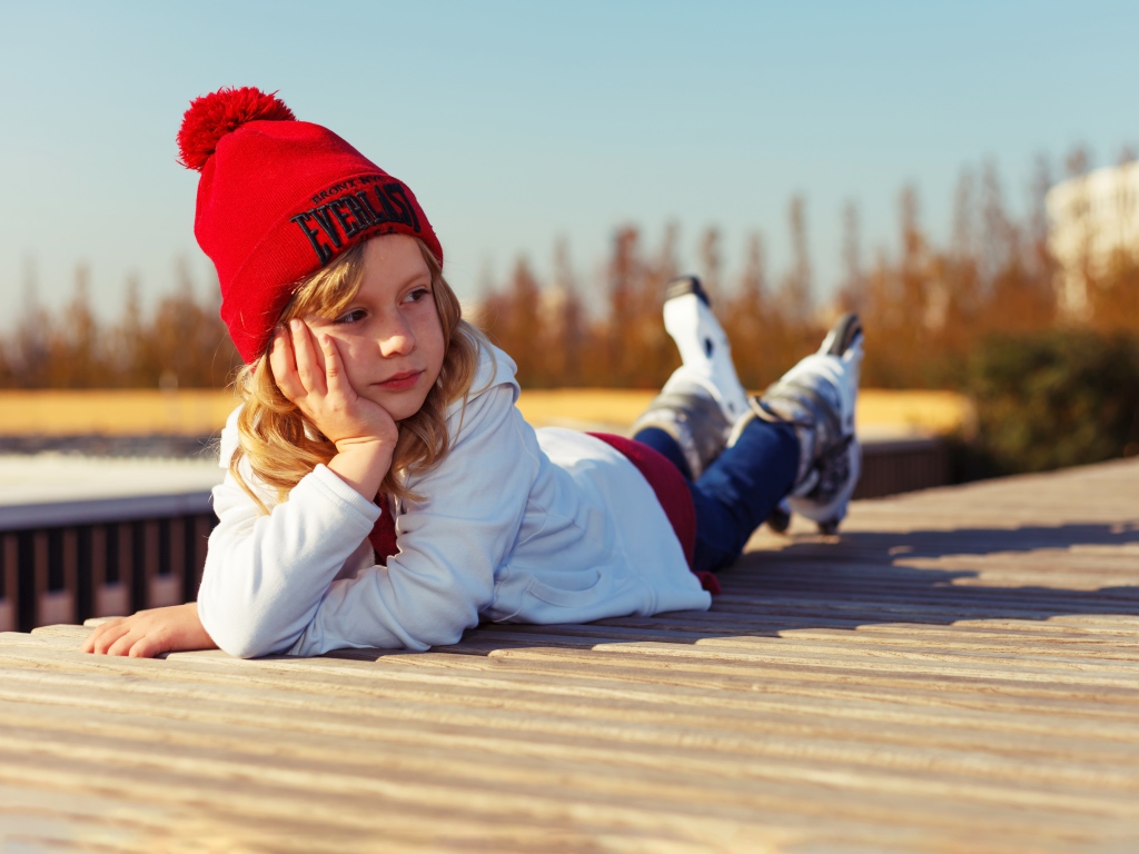 Маленькая девочка лежит на деревянном полу 