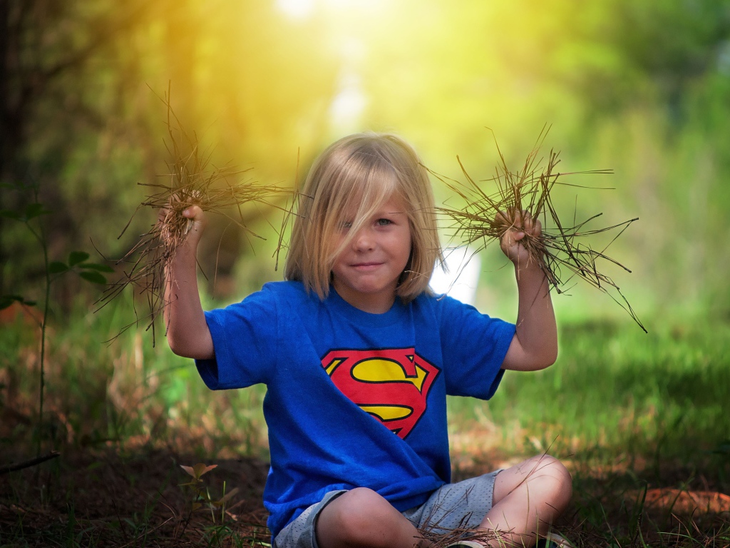 Маленькая девочка сидит на земле с травой