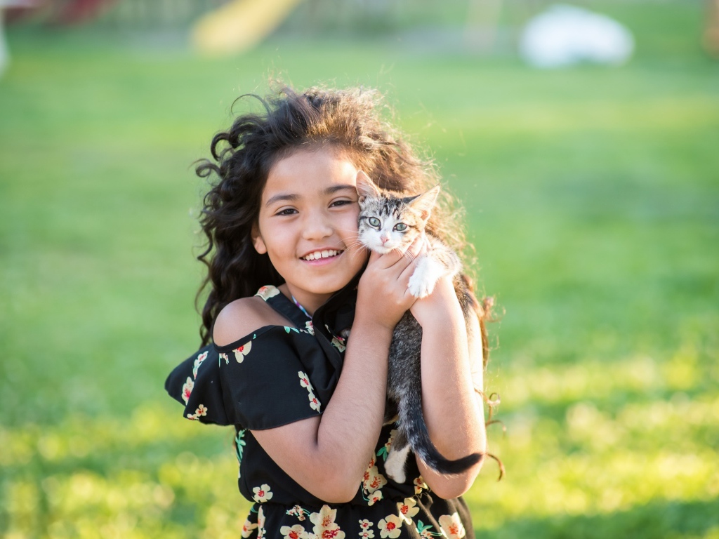 Маленькая улыбающаяся девочка с котенком в руках