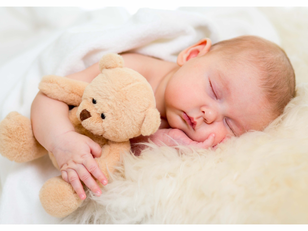 Новорожденный ребенок спит с игрушечным медведем