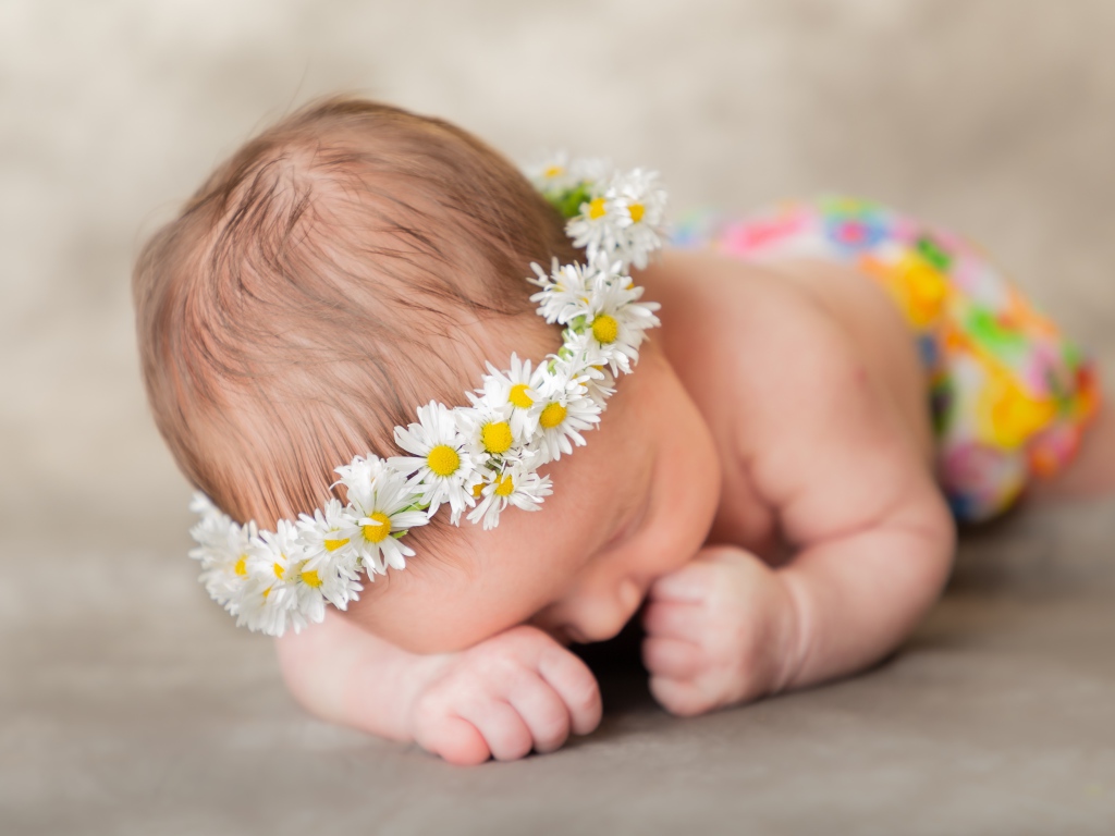 Спящий грудной ребенок в венке из ромашек 