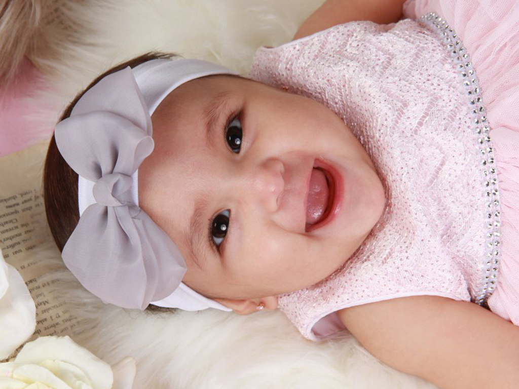 Улыбающаяся девочка в розовом платье с бантом на голове