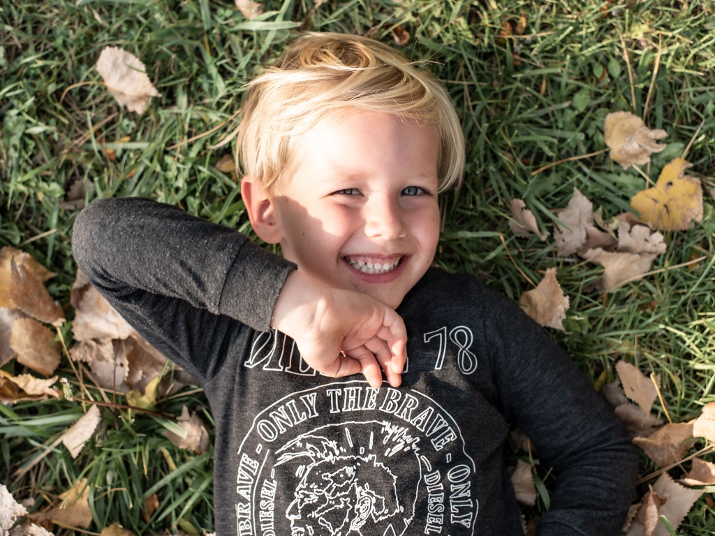 Улыбающийся маленький мальчик лежит на траве