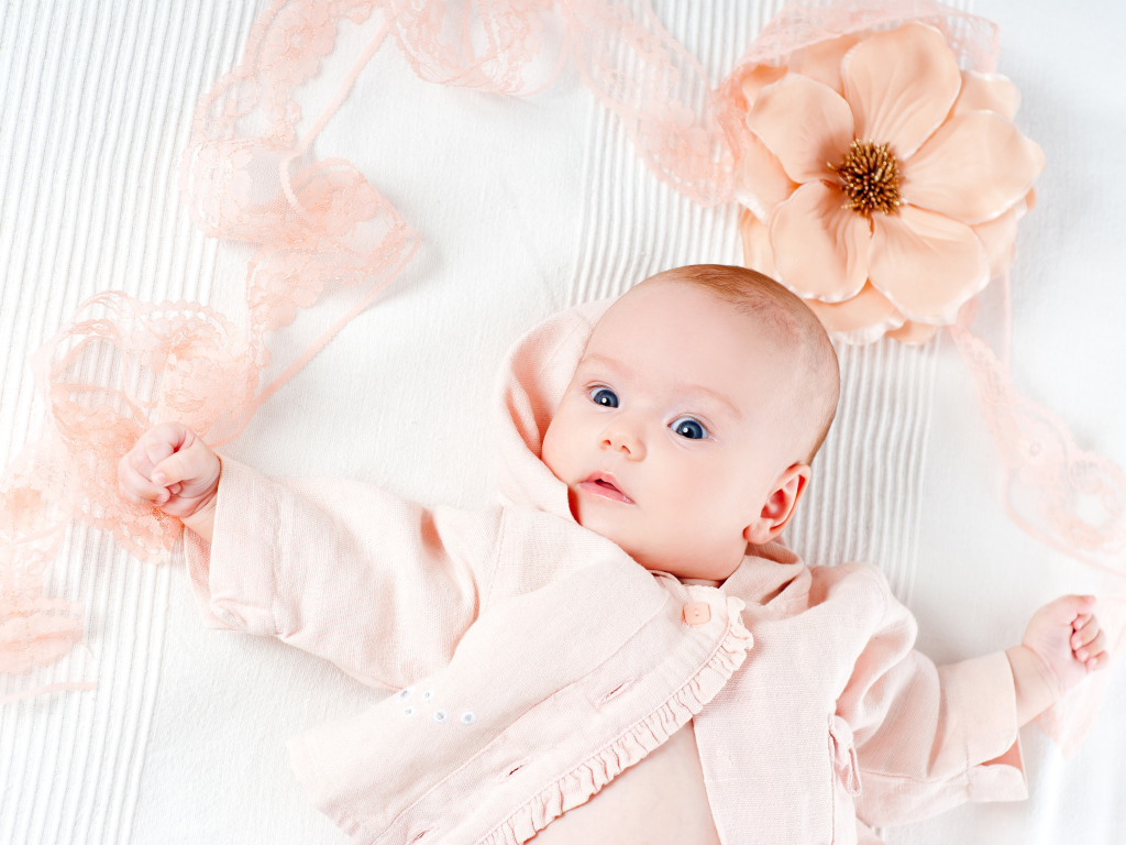 Удивленный новорожденный ребенок с цветком