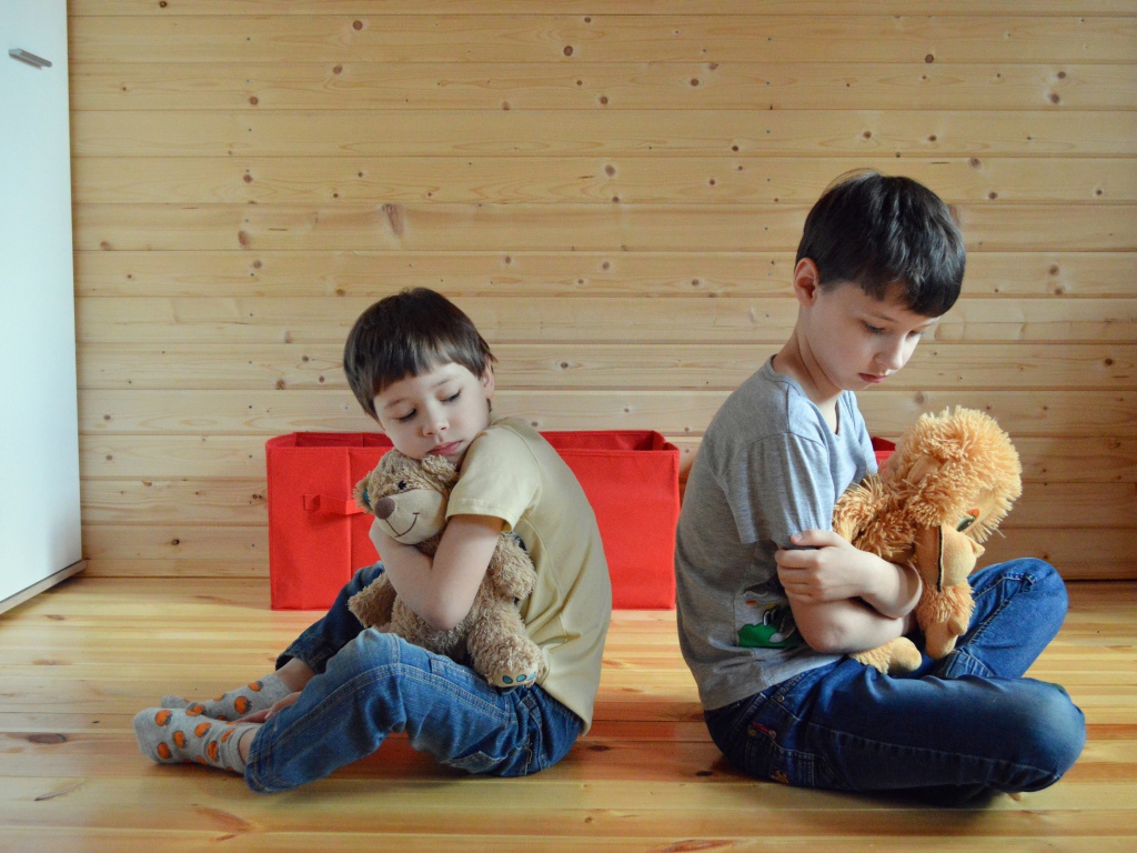 Два маленьких обиженных мальчика сидит на земле