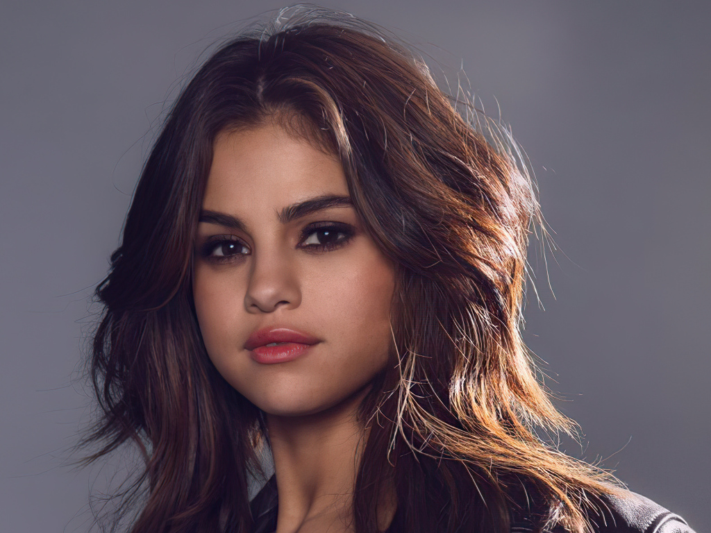 Лицо молодой девушки  Селены Гомез на сером фоне