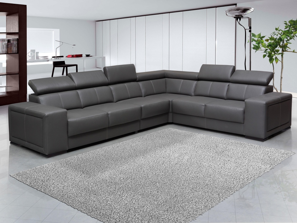 Большой черный угловой диван в комнате с белыми стенами