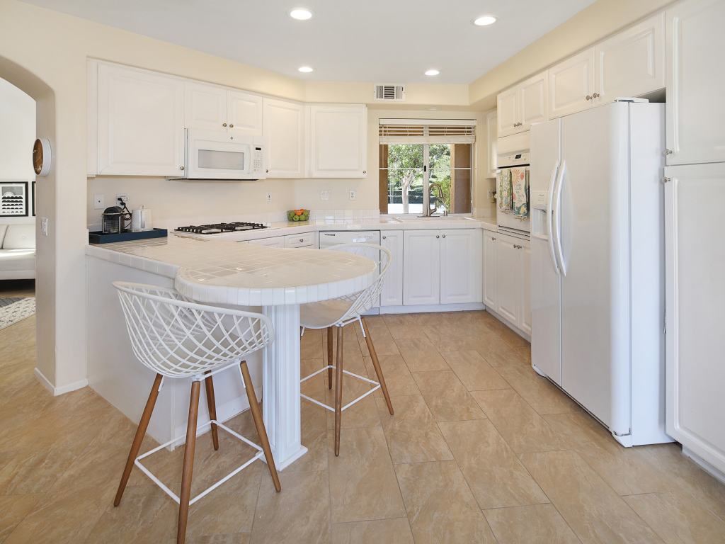 Большой холодильник и белая мебель на кухне 