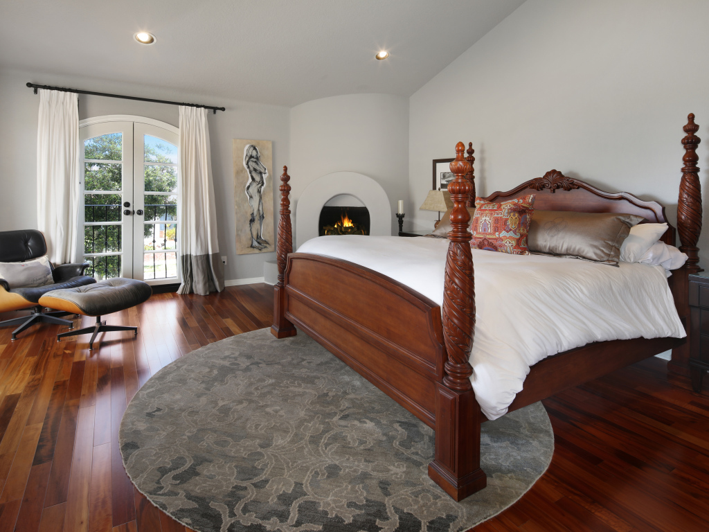 Большая деревянная кровать в спальне с камином 