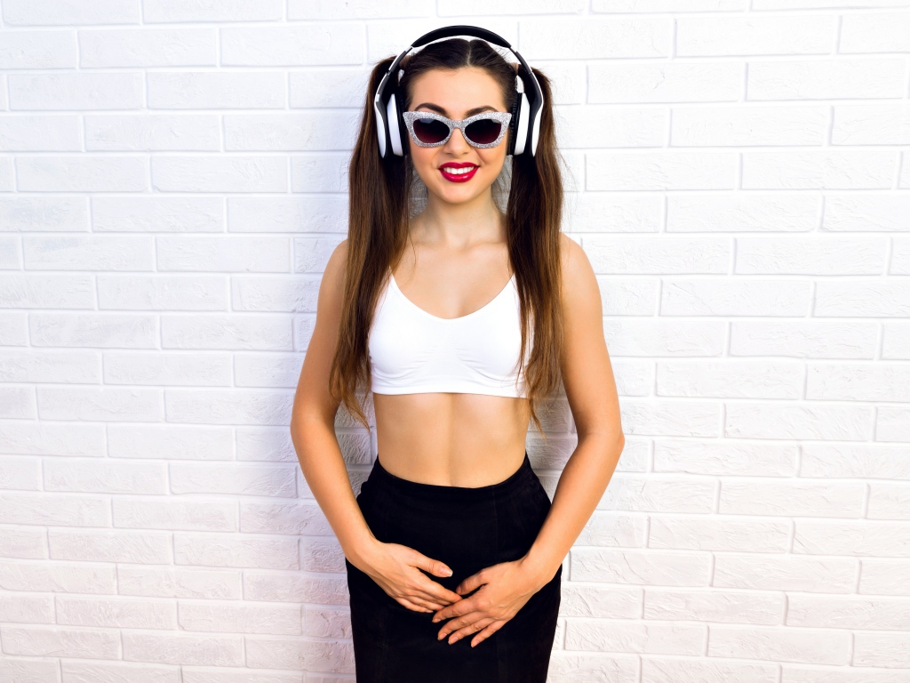 Спортивная девушка в очках у стены